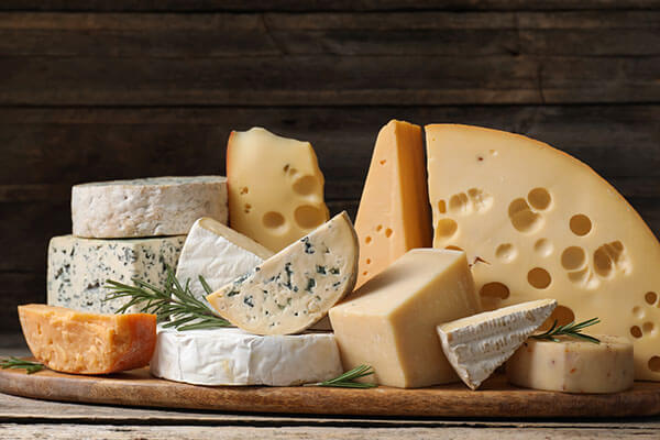 An assortment of cheeses on a wooden serving board