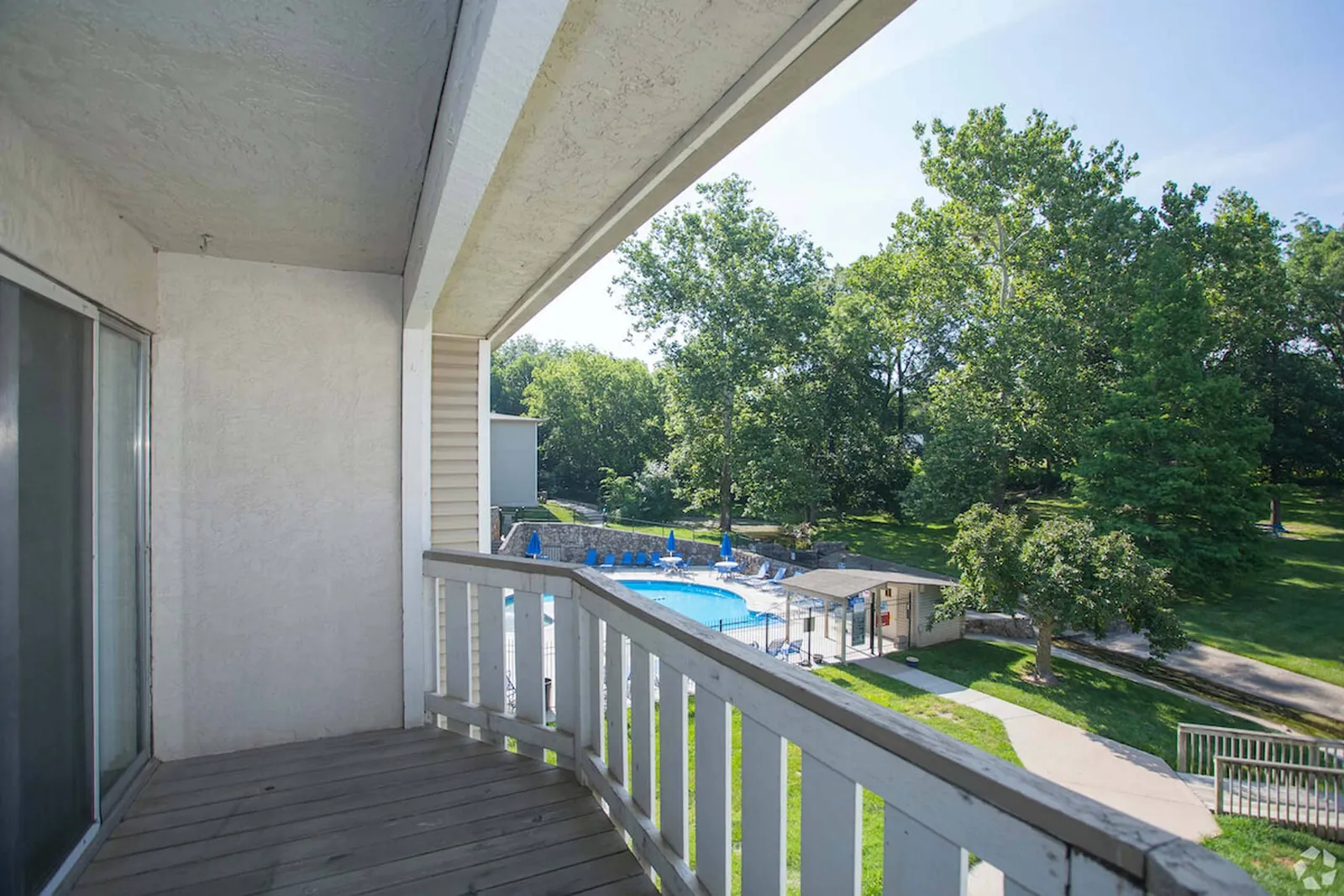 Forest Park Apartments - a balcony with a partial pool view and trees