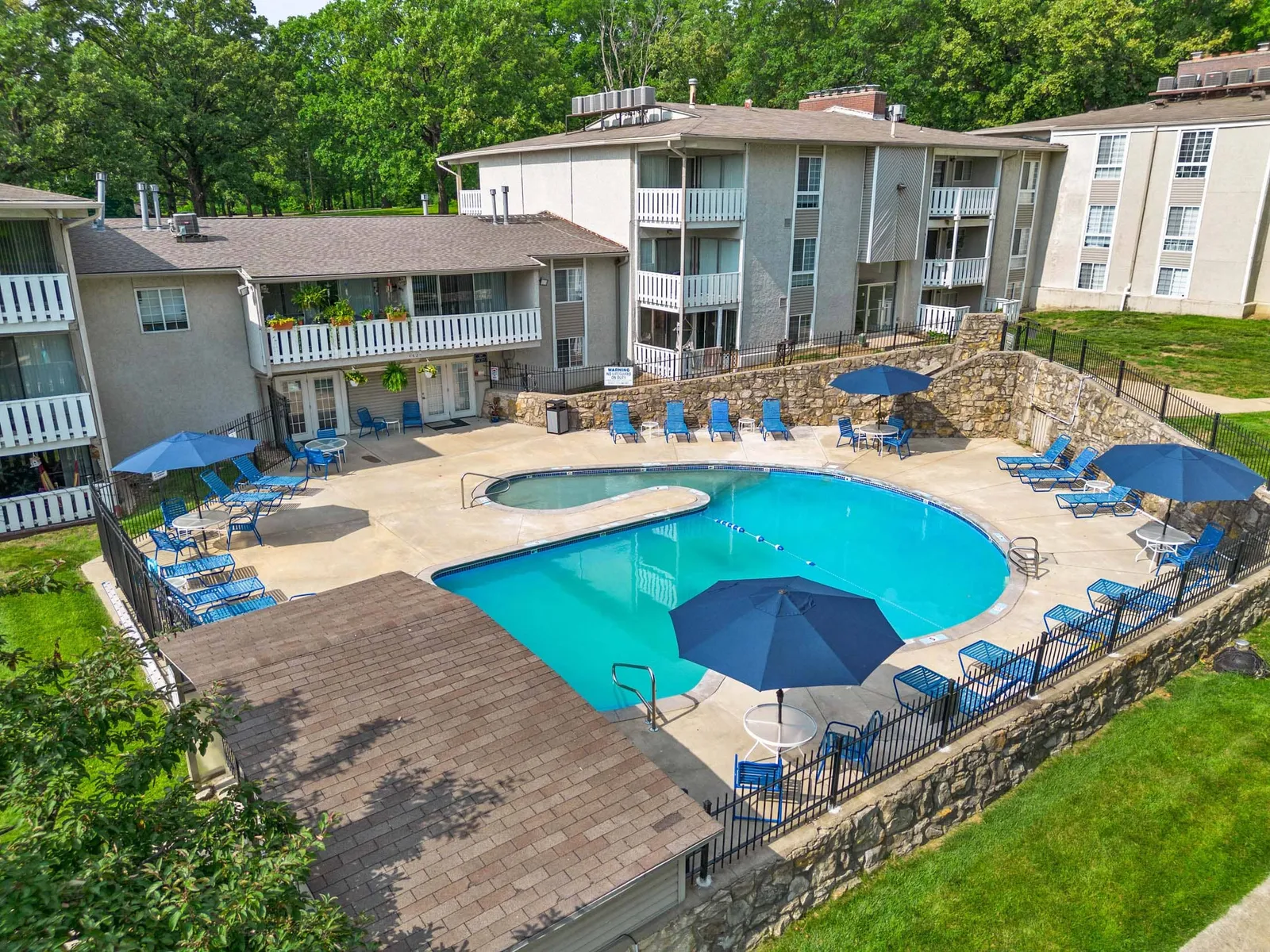 Forest Park Apartments - a pool surrounded by chairs and apartment buildings