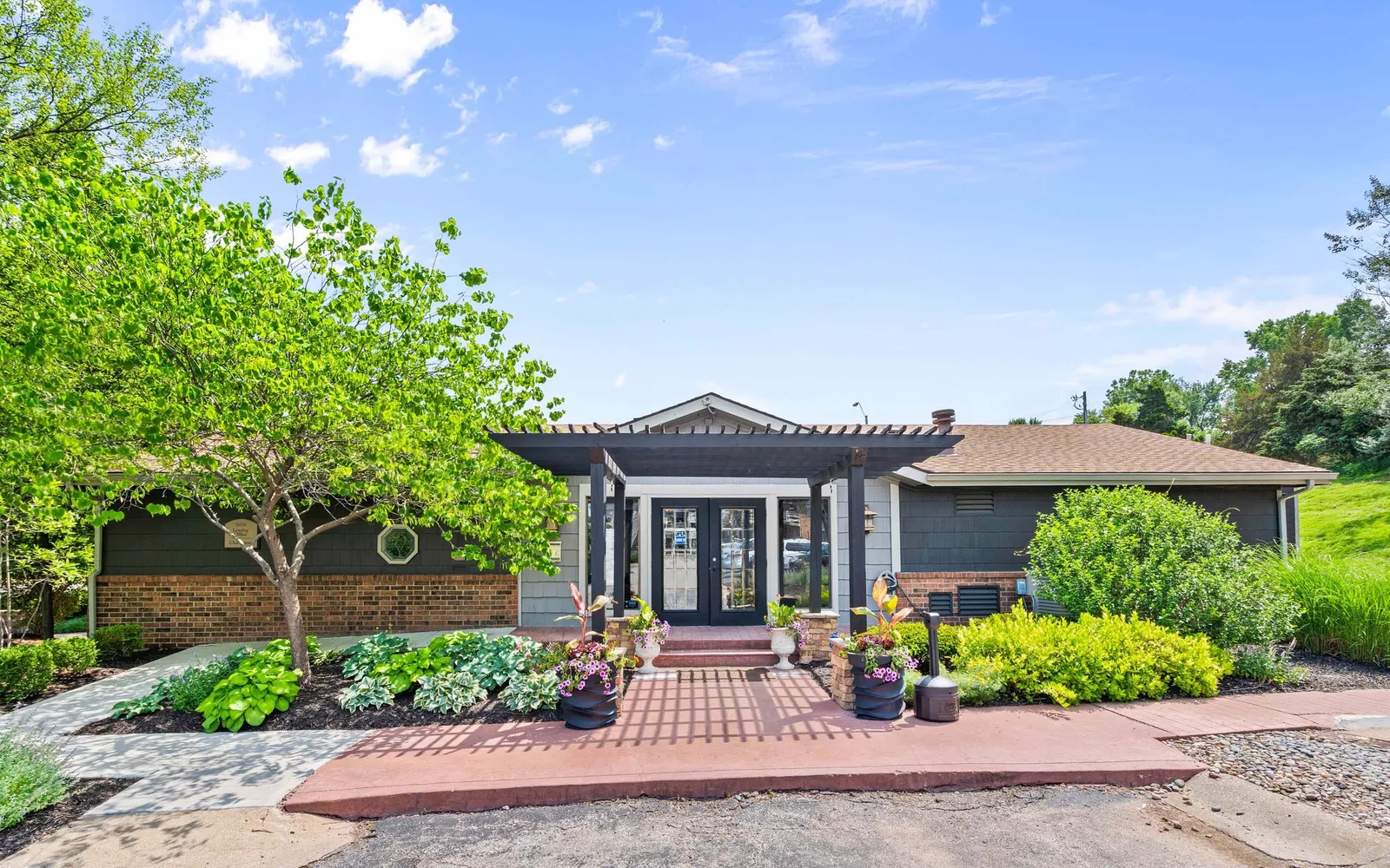 Prairie Walk Apartment Homes - a leasing office with a pathway and trees