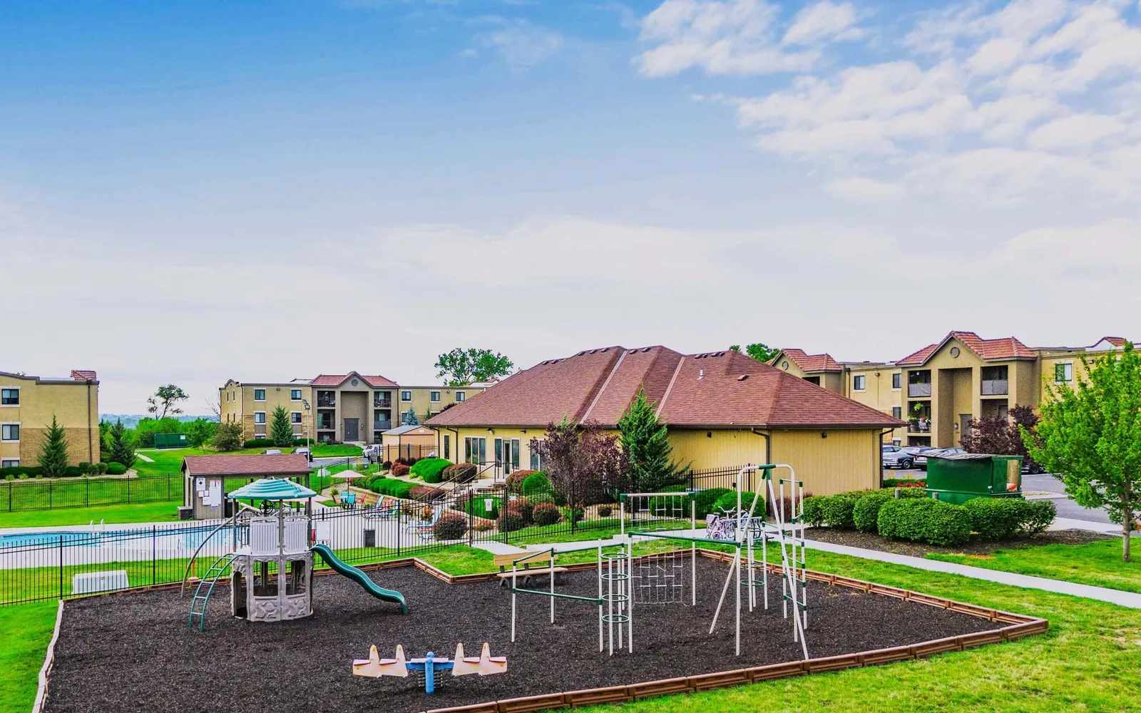 The Hills Apartments - a playground surrounded by grass and apartment buildings