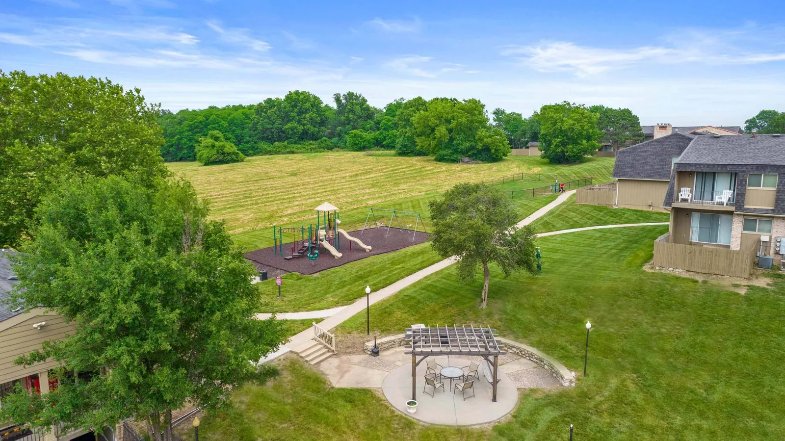 The Oaks at Prairie View - an aerial photo of a grass field, playground, and patio area