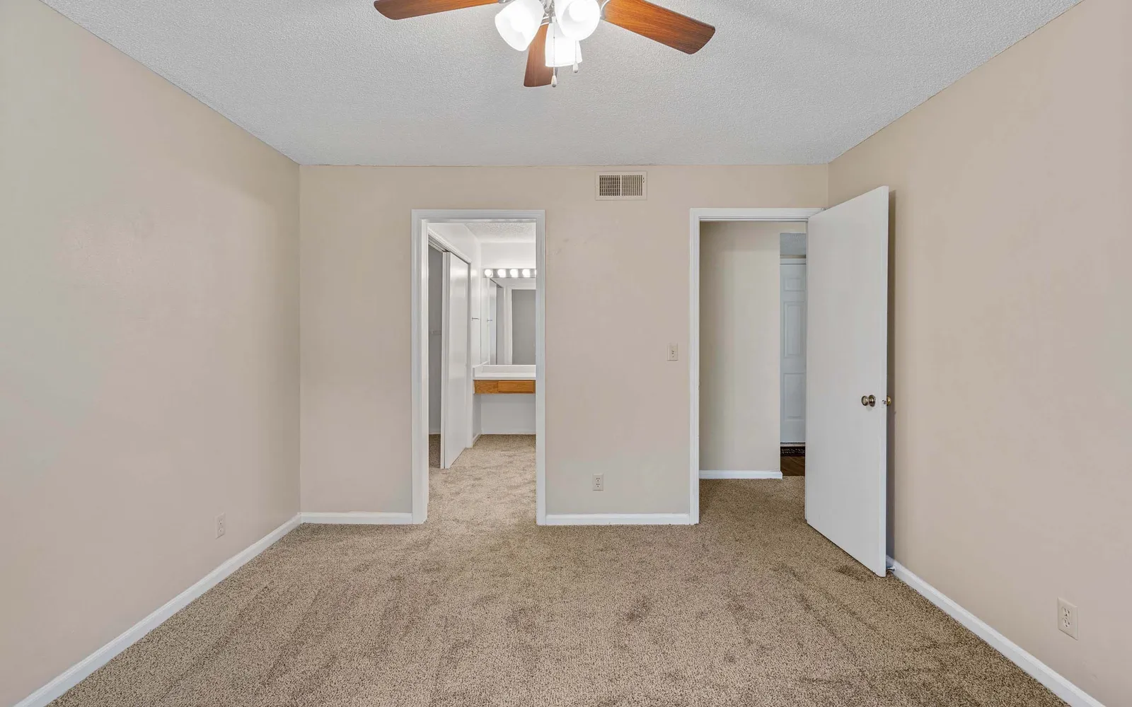 The Retreat at Woodlands - a bedroom with two open doors and a ceiling fan